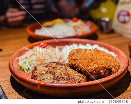 A luxurious combo meal featuring a hearty hamburger steak and a crispy minced meat cutlet. A luxurious combo meal featuring a hearty hamburger steak and a crispy minced meat cutlet. 140849838