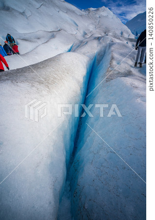Perito moreno glacier patagonia los glaciares national park hikers explore deep crevasse on bright ice under blue sky 140850226