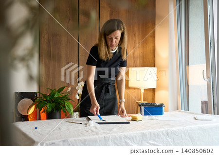 Woman artist creating textured picture on canvas at home Woman artist creating textured picture on canvas at home 140850602