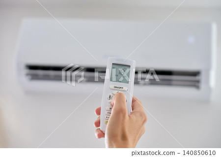 Hand adjusting temperature on air conditioner with remote control 140850610