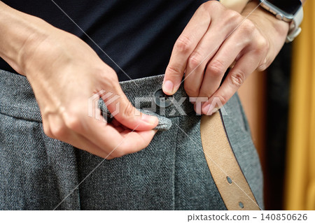Hands buttoning gray trousers Hands buttoning gray trousers 140850626