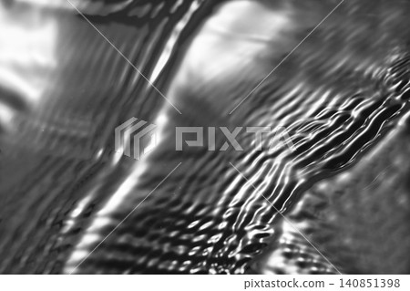 A shimmering, rippling water surface against a black background (background material/texture) A shimmering, rippling water surface against a black background (background material/texture) 140851398