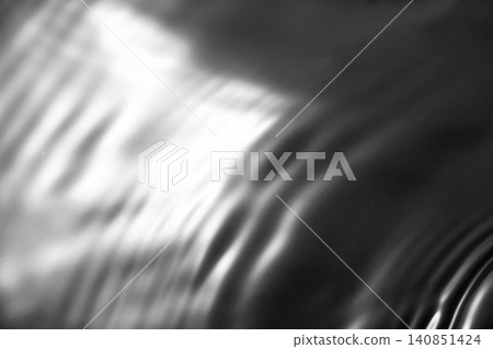 A shimmering, rippling water surface against a black background (background material/texture) A shimmering, rippling water surface against a black background (background material/texture) 140851424