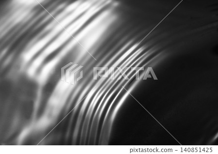 A shimmering, rippling water surface against a black background (background material/texture) A shimmering, rippling water surface against a black background (background material/texture) 140851425
