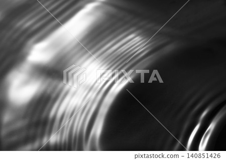 A shimmering, rippling water surface against a black background (background material/texture) A shimmering, rippling water surface against a black background (background material/texture) 140851426