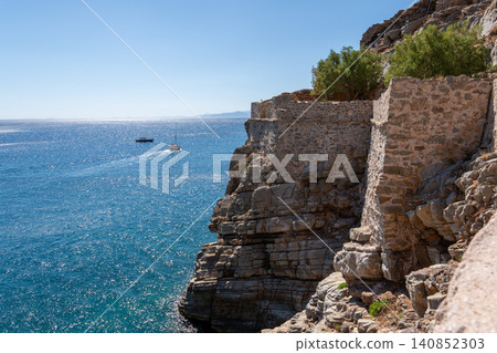 Historic Venetian fortress built on rocky cliff over blue sea on Spinalonga island Greece Historic Venetian fortress built on rocky cliff over blue sea on Spinalonga island Greece 140852303