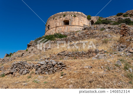 Round Venetian fortress bastion on rocky hillside under clear sky on Spinalonga Greece Round Venetian fortress bastion on rocky hillside under clear sky on Spinalonga Greece 140852314