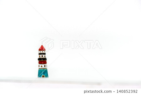 Miniature lighthouse decoration with red cap and blue base on a white background Miniature lighthouse decoration with red cap and blue base on a white background 140852392