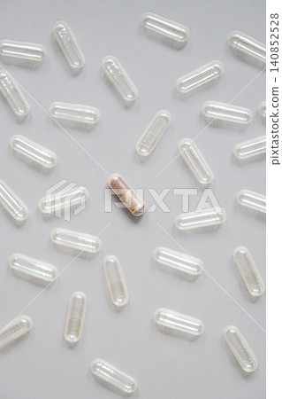 Single filled medicine capsule among empty transparent pill shells. Single filled medicine capsule among empty transparent pill shells. 140852528