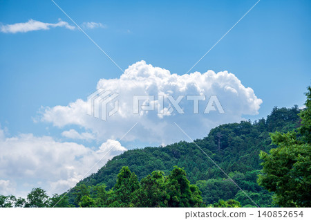 白色的積雨雲漂浮在藍天和夏季的山脈之間 白色的積雨雲漂浮在藍天和夏季的山脈之間 140852654