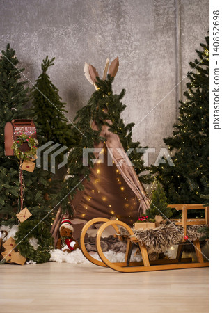 Cozy children's Christmas teepee with fairy lights, wooden sled and holiday decor Cozy children's Christmas teepee with fairy lights, wooden sled and holiday decor 140852698
