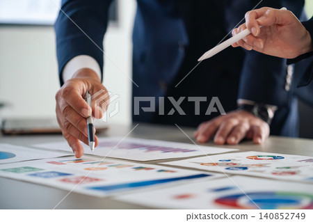 A group of business people talking while looking at documents. Marketing, research, meetings, planning 140852749