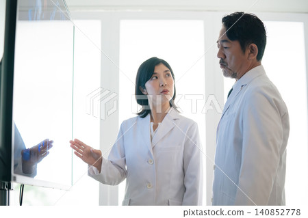 一群男女醫生一邊看著螢幕一邊交談。醫生、科學家、研究人員、會議、會診、白大褂、醫院 一群男女醫生一邊看著螢幕一邊交談。醫生、科學家、研究人員、會議、會診、白大褂、醫院 140852778