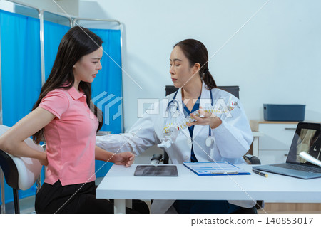 Doctor explains spine surgery using anatomical model, explaining symptoms and treatment to patients. 140853017