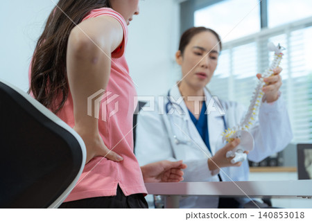 Doctor explains spine surgery using anatomical model, explaining symptoms and treatment to patients. 140853018
