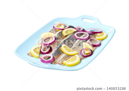 herring fillet with red onion rings and lemon on a blue plate isolated on a white background. herring fillet with red onion rings and lemon on a blue plate isolated on a white background. 140853286