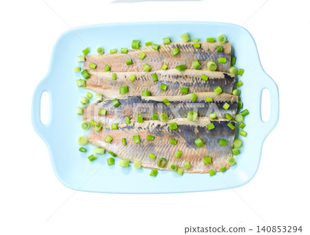 herring fillet with green onions on a blue plate isolated on a white background, top view. 140853294