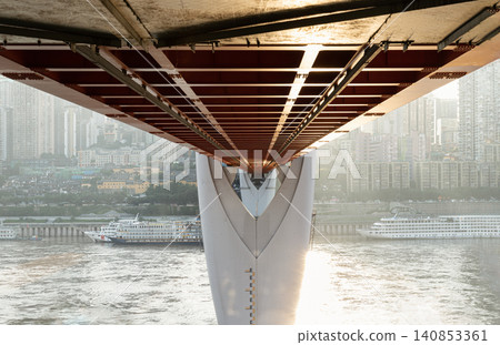 the bold red and white underbelly of the Qiansimen Bridge part of the famed Twin River Bridges elegantly frames Chongqing shimmering waters, cruising ships, and sprawling, mist-shrouded skyline. the bold red and white underbelly of the Qiansimen Bridge part of the famed Twin River Bridges elegantly frames Chongqing shimmering waters, cruising ships, and sprawling, mist-shrouded skyline. 140853361