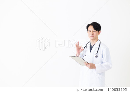 A middle-aged male doctor in a white coat makes a circular pose while holding a binder. A middle-aged male doctor in a white coat makes a circular pose while holding a binder. 140853395