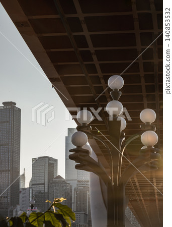 an intimate look beneath Chongqing iconic infrastructure, where a detailed white globe street lamp stands in sharp focus against the massive gridwork of the bridge deck and a hazy, towering urban an intimate look beneath Chongqing iconic infrastructure, where a detailed white globe street lamp stands in sharp focus against the massive gridwork of the bridge deck and a hazy, towering urban 140853532