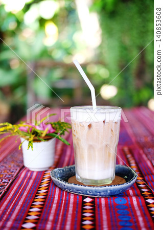 Fresh a clear glass of iced latte coffee with milk foam on table in garden 140853608