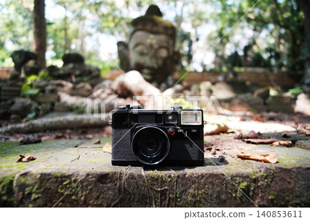 Vintage black analog film camera on the rock at Ancient of buddha statue in ancient temple in Chiang Mai of Thailand Vintage black analog film camera on the rock at Ancient of buddha statue in ancient temple in Chiang Mai of Thailand 140853611