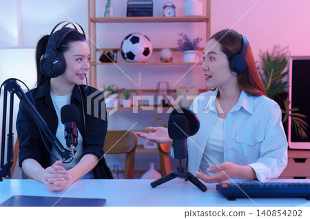 Two Asian women recording podcast episode in creative home studio Two Asian women recording podcast episode in creative home studio 140854202