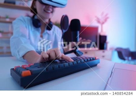 Asian woman wearing VR headset typing on keyboard for virtual reality gaming Asian woman wearing VR headset typing on keyboard for virtual reality gaming 140854284