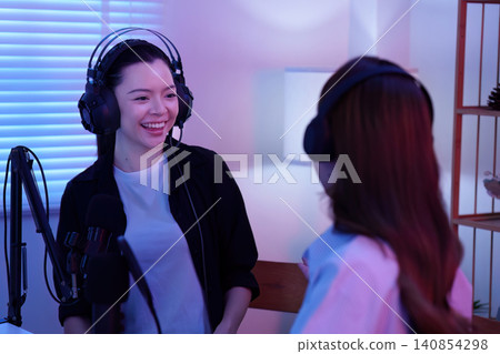 Two Asian women recording podcast in home studio with microphone Two Asian women recording podcast in home studio with microphone 140854298