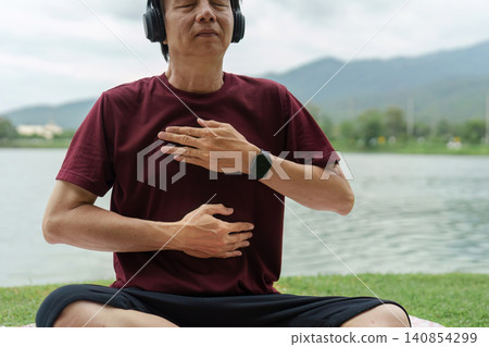 Asian senior man practicing mindful breathing exercise by lake 140854299
