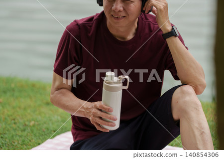 Asian senior man holding water bottle outdoors for hydration and healthy lifestyle 140854306