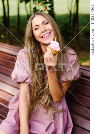 Smiling Woman With Cupcake Outdoors Smiling Woman With Cupcake Outdoors 140854368
