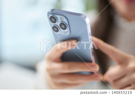 一位二十多歲的女性正在看她的智慧型手機。 一位二十多歲的女性正在看她的智慧型手機。 140855219