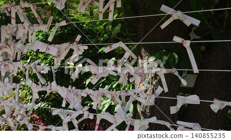 A scene of many fortune slips tied to a string in the temple grounds. A scene of many fortune slips tied to a string in the temple grounds. 140855235