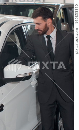 Vertical Video Stylish man is choosing new automobile walking around luxury car and touching it in car dealership. Rich people, transportation and business class vehicles concept. Vertical Video Stylish man is choosing new automobile walking around luxury car and touching it in car dealership. Rich people, transportation and business class vehicles concept. 140855550