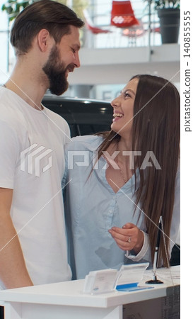 Vertical Video Seller signing contract, passing pen to person. Young individual adding signature to document. Seller handing over car keys amidst stunning new vehicles. Vertical Video Seller signing contract, passing pen to person. Young individual adding signature to document. Seller handing over car keys amidst stunning new vehicles. 140855555