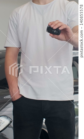 Vertical Video Man customer holding out car keys to his newly bought car. Man holding car keys standing at the dealership salon consumerism vehicle luxury transportation concept. Vertical Video Man customer holding out car keys to his newly bought car. Man holding car keys standing at the dealership salon consumerism vehicle luxury transportation concept. 140855578