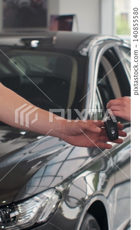 Vertical Video Female hand gives a car keys to male hand in the car dealership close up. Unrecognized auto seller and a woman who bought a vehicle shake hands. Vertical Video Female hand gives a car keys to male hand in the car dealership close up. Unrecognized auto seller and a woman who bought a vehicle shake hands. 140855580