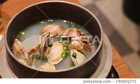 close up of Sake Steamed Clams in a pot served in a traditional metal pot, featuring fresh clams with open shells in a clear, savory broth, garnished with chopped green onions with copy space close up of Sake Steamed Clams in a pot served in a traditional metal pot, featuring fresh clams with open shells in a clear, savory broth, garnished with chopped green onions with copy space 140856771