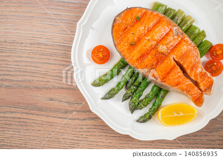 Grilled salmon steak with asparagus and lemon on white plate top view Grilled salmon steak with asparagus and lemon on white plate top view 140856935