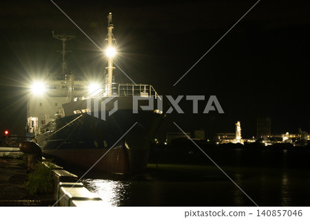 Ships anchored in the harbor at night, with the factory lights visible in the distance. Ships anchored in the harbor at night, with the factory lights visible in the distance. 140857046