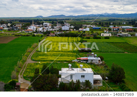 Rolling green fields and charming villages flourish under cloudy skies in tranquil countryside vistas of a rural landscape Rolling green fields and charming villages flourish under cloudy skies in tranquil countryside vistas of a rural landscape 140857569