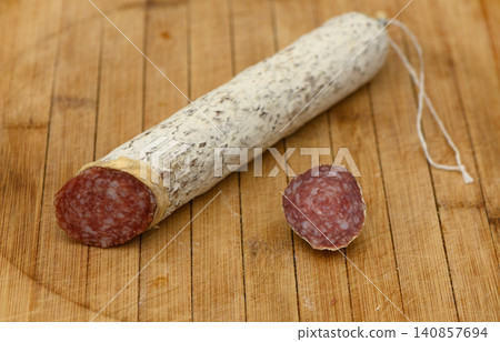 Savory artisanal salami resting on a wooden cutting board during a cozy kitchen moment Savory artisanal salami resting on a wooden cutting board during a cozy kitchen moment 140857694