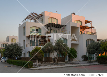 Modern white buildings basking in the warm glow of the evening sun on a peaceful residential street Modern white buildings basking in the warm glow of the evening sun on a peaceful residential street 140857696