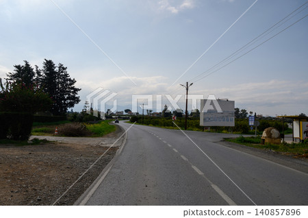Scenic rural road winding through a lush landscape under a cloudy sky in mid-afternoon 140857896