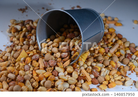 Colorful assortment of nuts spills from tin container creating a vibrant snack display on a bright surface 140857950