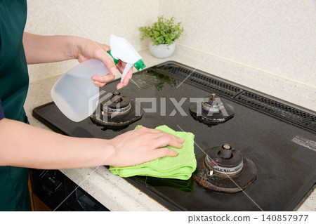 The hands wiping down the gas stove The hands wiping down the gas stove 140857977