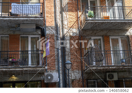 Wicker Hanging Swing Chair on Apartment Balcony Overlooking Courtyard Wicker Hanging Swing Chair on Apartment Balcony Overlooking Courtyard 140858062