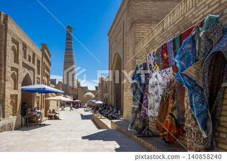 A scene of minarets and souvenir shops seen in Ichan Kala, Khiva, Uzbekistan. A scene of minarets and souvenir shops seen in Ichan Kala, Khiva, Uzbekistan. 140858240
