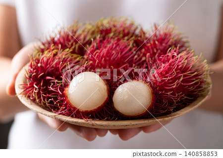 Fresh rambutan fruit in natural plate holding by woman hand, Tropical summer fruit in Thailand Fresh rambutan fruit in natural plate holding by woman hand, Tropical summer fruit in Thailand 140858853